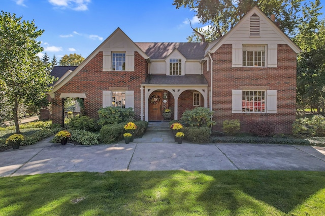 view of front facade featuring a front yard, brick siding, and roof with shingles