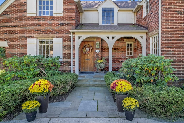 entrance to property featuring a porch and brick siding