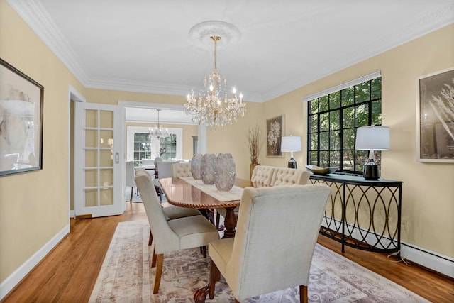 dining area featuring a chandelier, a healthy amount of sunlight, crown molding, and wood finished floors