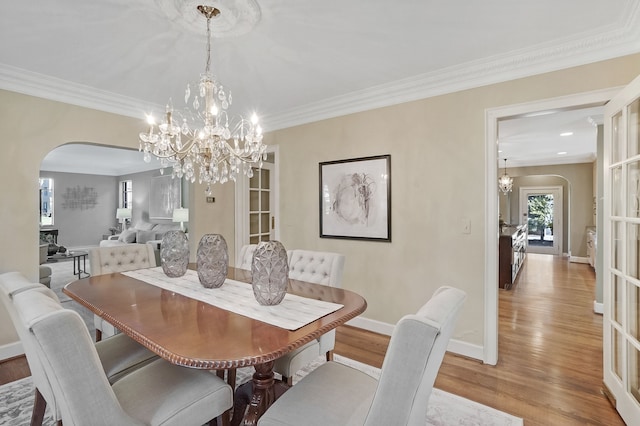 dining area featuring arched walkways, crown molding, baseboards, and wood finished floors