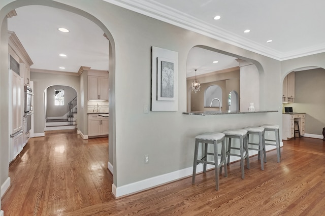 kitchen featuring baseboards, ornamental molding, a kitchen breakfast bar, wood finished floors, and backsplash