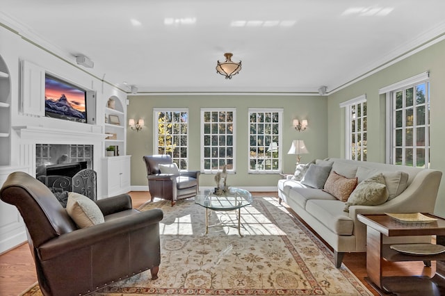 living room featuring a fireplace, built in features, crown molding, and wood finished floors