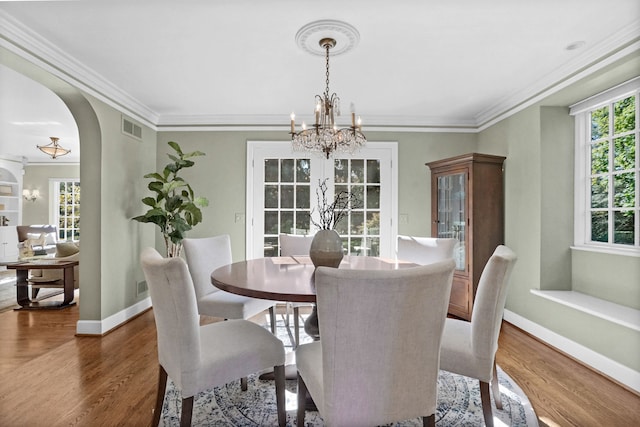 dining space with arched walkways, dark wood-style flooring, a chandelier, and visible vents