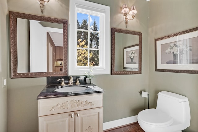 half bath featuring toilet, baseboards, and vanity