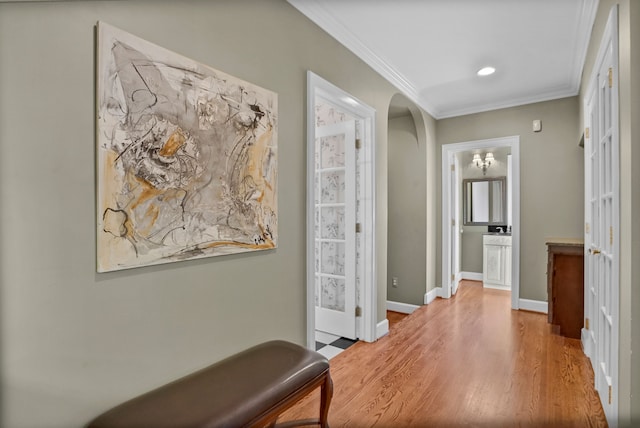 hallway with baseboards, arched walkways, crown molding, and wood finished floors