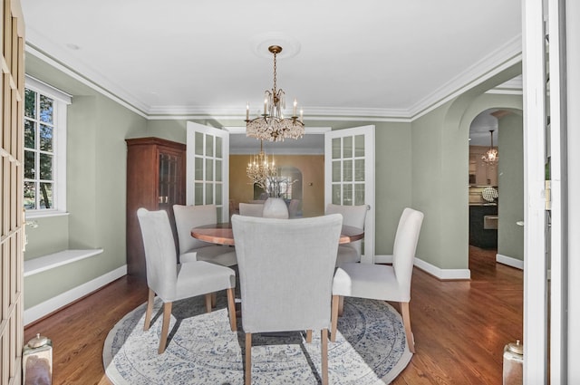 dining room with arched walkways, a notable chandelier, baseboards, and wood finished floors