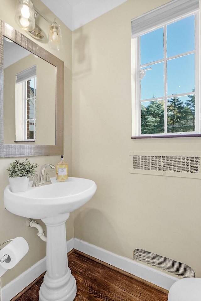 half bath with toilet, baseboards, visible vents, and wood finished floors