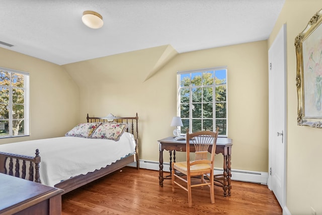 bedroom with multiple windows, baseboard heating, and wood finished floors