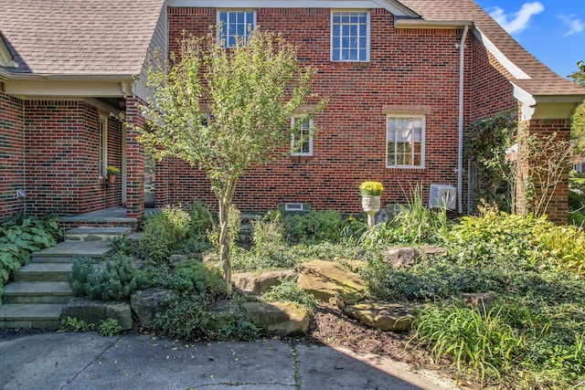 view of property exterior with a shingled roof and brick siding