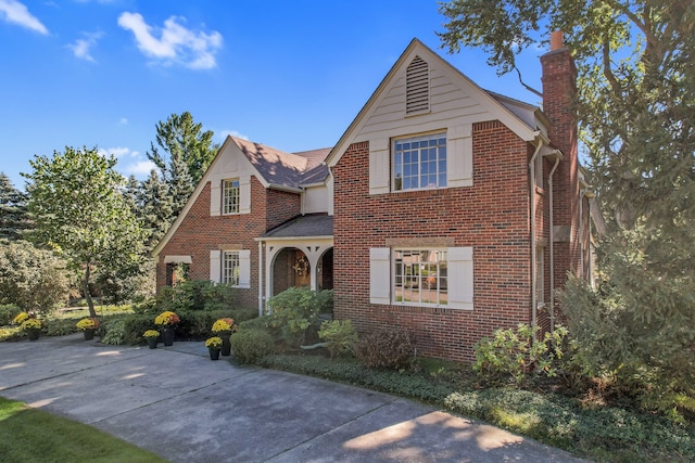 view of front facade featuring a chimney and brick siding