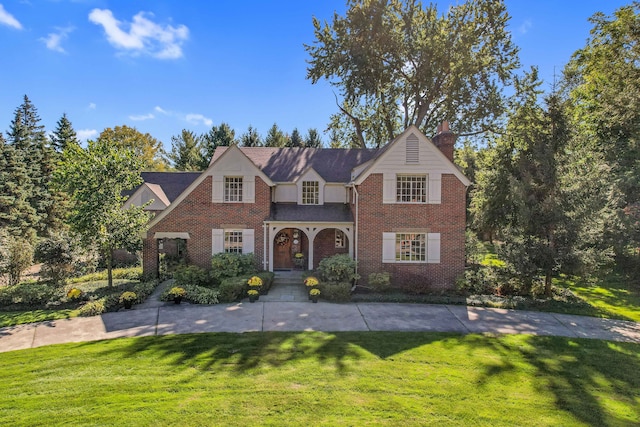 traditional-style home with brick siding, a chimney, and a front yard