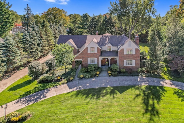 view of front of property with a front yard, brick siding, and a chimney