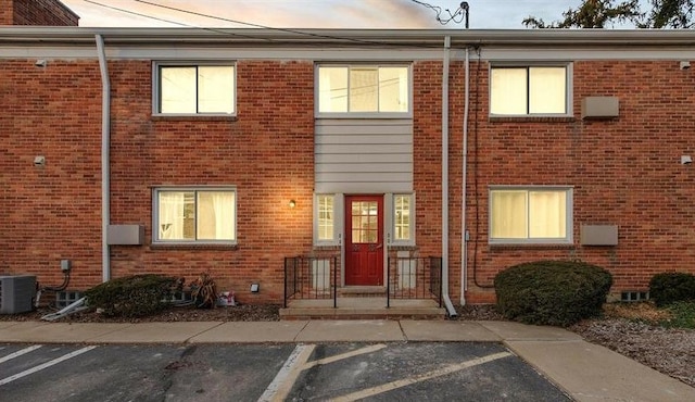 exterior space featuring uncovered parking, cooling unit, and brick siding