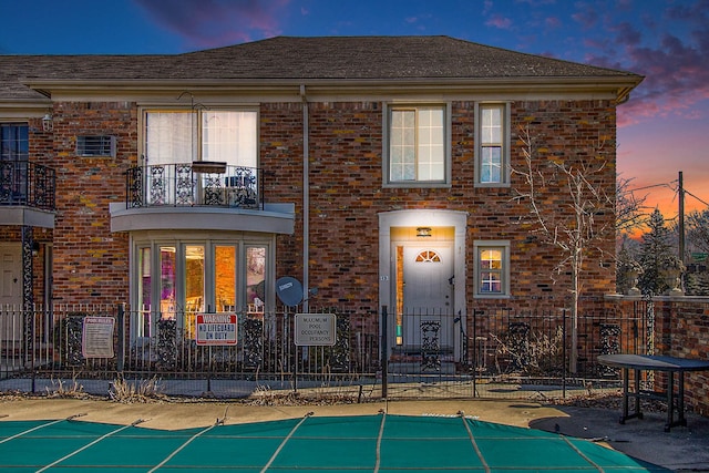 exterior space with brick siding, fence, and a balcony