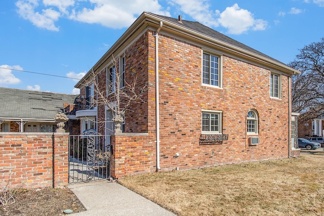 view of property exterior featuring a yard, a gate, brick siding, and fence