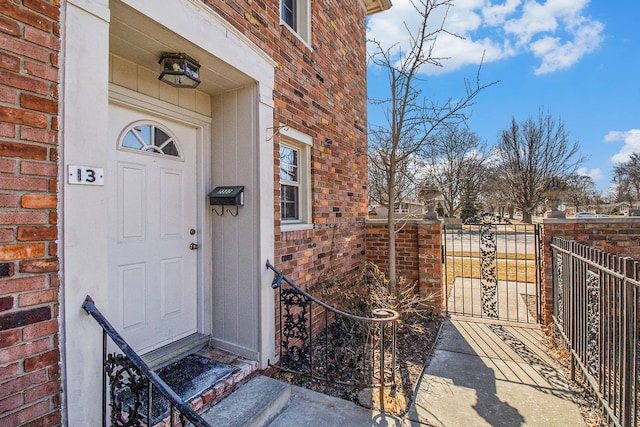 property entrance with brick siding, fence, and a gate