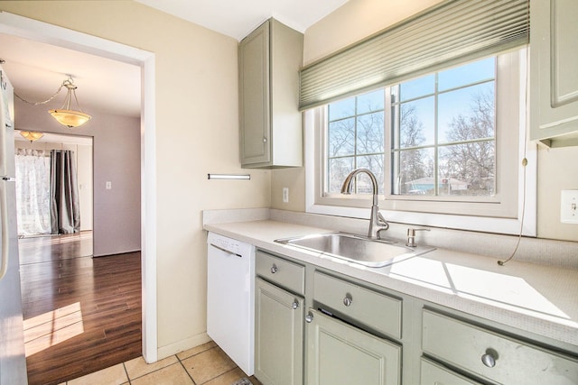 kitchen featuring light tile patterned floors, white dishwasher, light countertops, and a sink