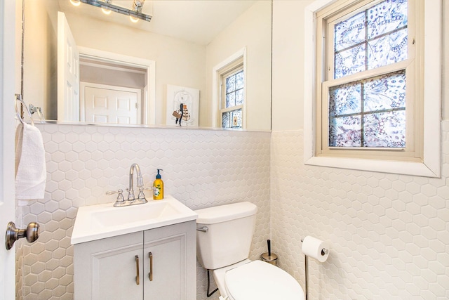 half bath with vanity, toilet, and tile walls