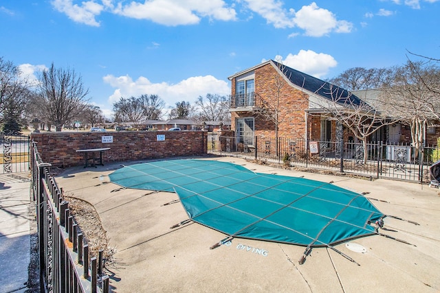 community pool with a patio area and fence