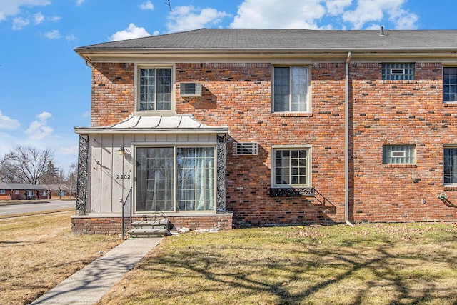 rear view of house featuring a yard, brick siding, and board and batten siding