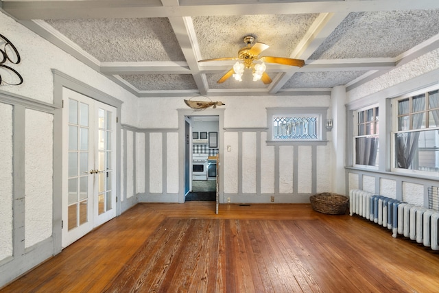 interior space featuring beam ceiling, french doors, radiator heating unit, ceiling fan, and coffered ceiling