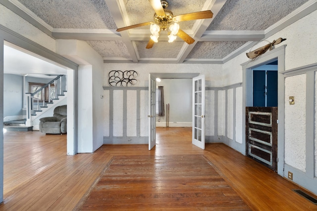 unfurnished dining area featuring visible vents, coffered ceiling, wood-type flooring, french doors, and beam ceiling