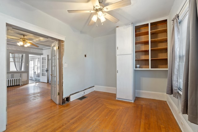 spare room with radiator, visible vents, ceiling fan, baseboards, and hardwood / wood-style flooring