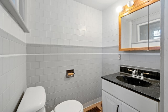 bathroom with toilet, visible vents, tile walls, and vanity