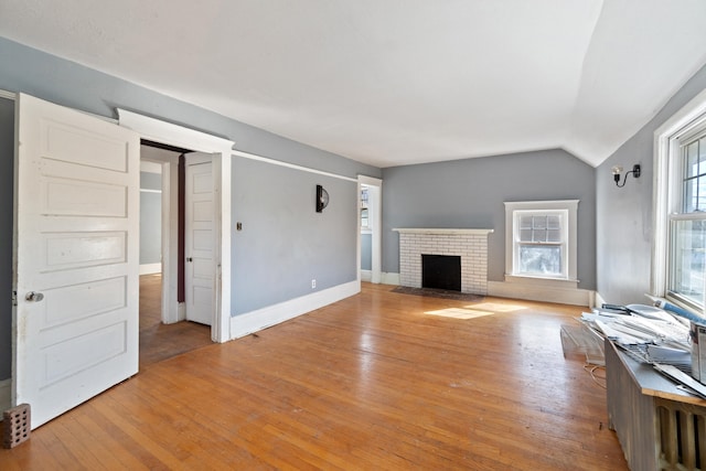 unfurnished living room with lofted ceiling, light wood-style floors, a fireplace, and baseboards