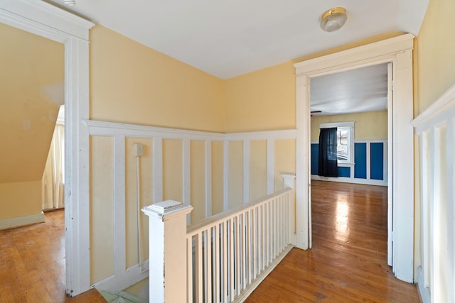 hall with a wainscoted wall, an upstairs landing, and wood finished floors