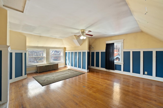 bonus room featuring a ceiling fan, vaulted ceiling, radiator, hardwood / wood-style floors, and attic access