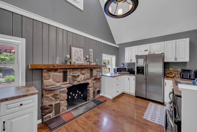 12260 183rd Ave, Big Rapids, MI 49307 - kitchen featuring appliances with stainless steel finishes, high vaulted ceiling, white cabinets, wood finished floors, and a fireplace