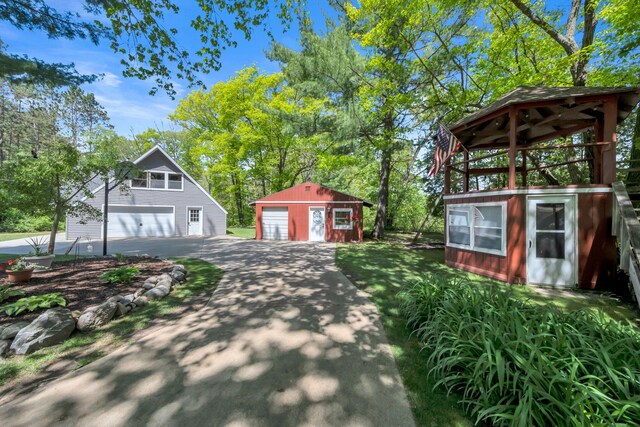 12260 183rd Ave, Big Rapids, MI 49307 - view of front facade featuring a detached garage, asphalt driveway, and an outbuilding