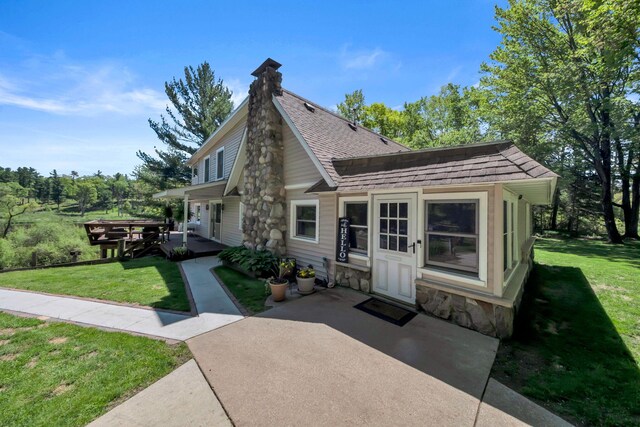 12260 183rd Ave, Big Rapids, MI 49307 - back of property with a patio area, a yard, stone siding, and roof with shingles
