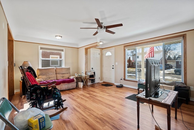 living room featuring light wood-style flooring, baseboards, and ceiling fan