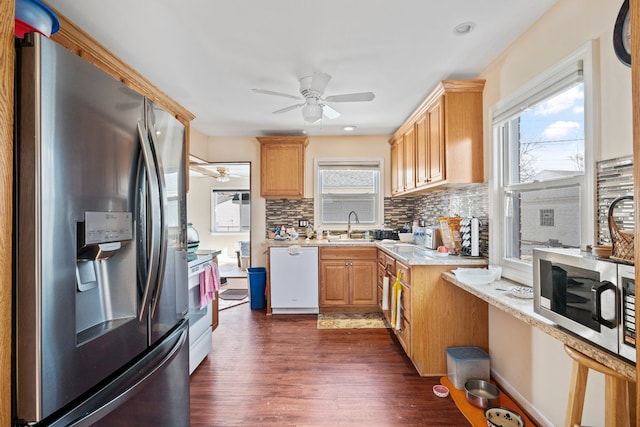 kitchen featuring stainless steel appliances, dark wood-type flooring, a sink, light countertops, and tasteful backsplash