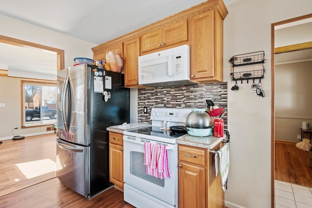 kitchen with white appliances, baseboards, decorative backsplash, light countertops, and light wood-style floors