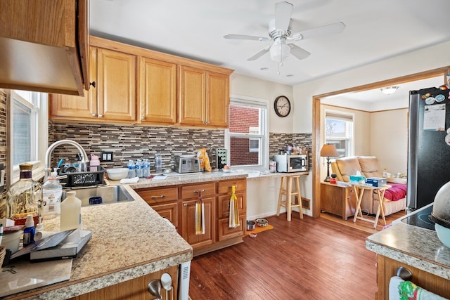 kitchen featuring a sink, light countertops, appliances with stainless steel finishes, decorative backsplash, and dark wood finished floors