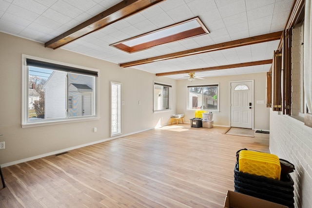 foyer entrance featuring baseboards, wood finished floors, beam ceiling, and a healthy amount of sunlight