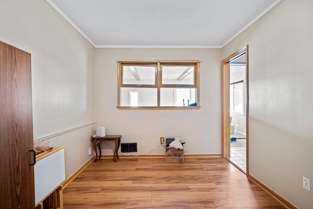 empty room featuring light wood-type flooring, visible vents, and crown molding