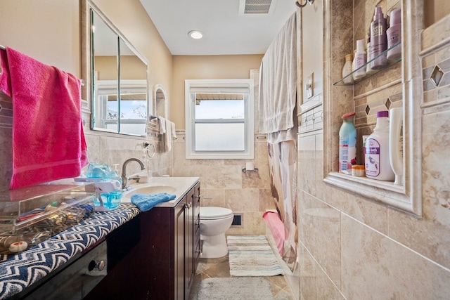 full bathroom featuring visible vents, toilet, tile patterned flooring, vanity, and tile walls