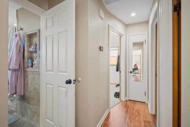 hallway featuring light wood-style flooring and baseboards