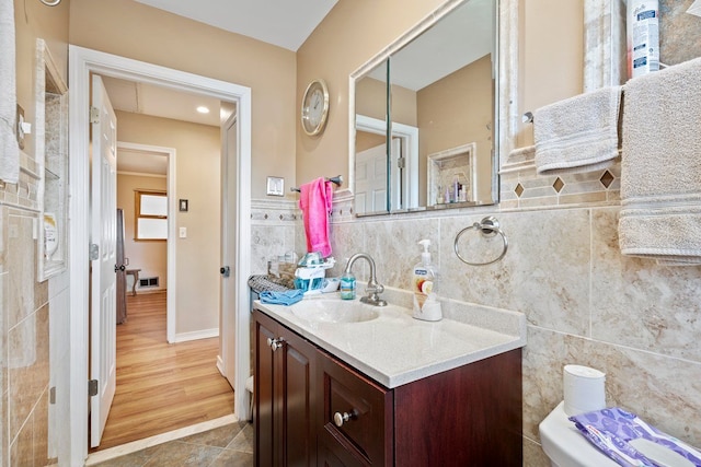 bathroom featuring visible vents, tile walls, and vanity