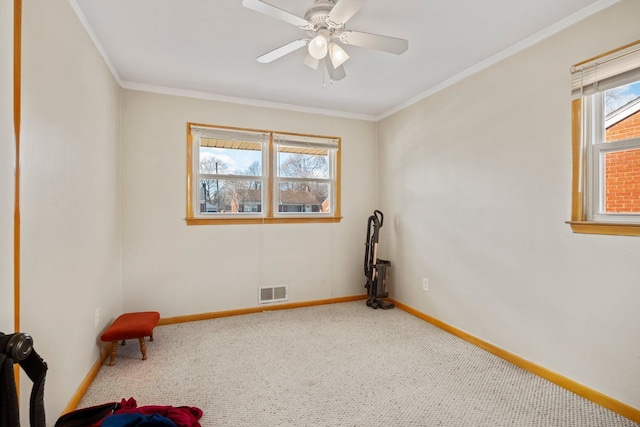 carpeted spare room with crown molding, plenty of natural light, visible vents, and baseboards