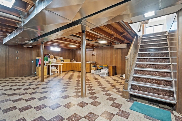 below grade area featuring stairway, wood walls, and tile patterned floors