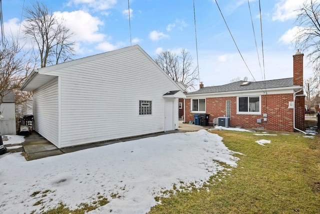 back of property with a garage, central AC, brick siding, and a chimney