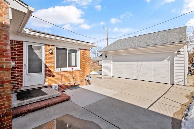 entrance to property with a garage, brick siding, and roof with shingles