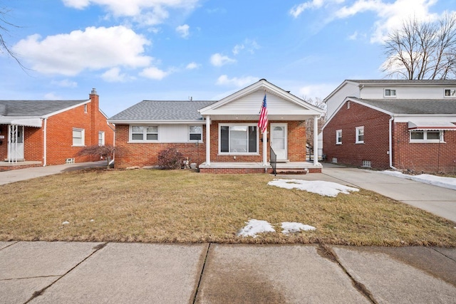 view of front of house with covered porch, a front lawn, and brick siding