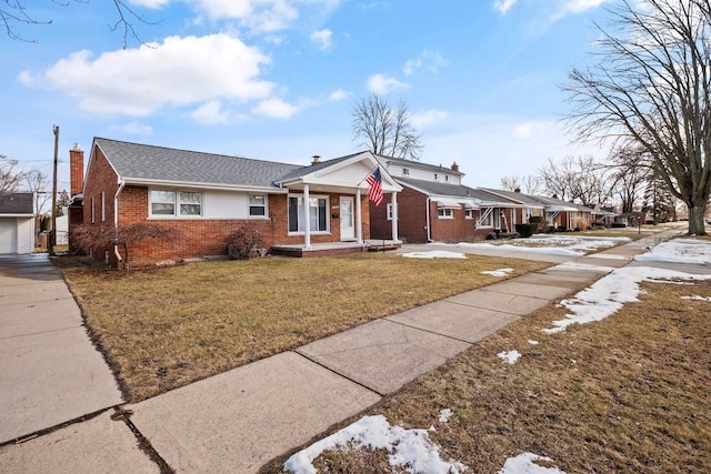 view of front facade with an outdoor structure, a chimney, a front lawn, and brick siding