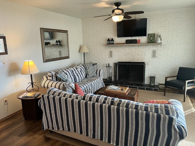 living area featuring a brick fireplace, brick wall, a ceiling fan, and wood finished floors